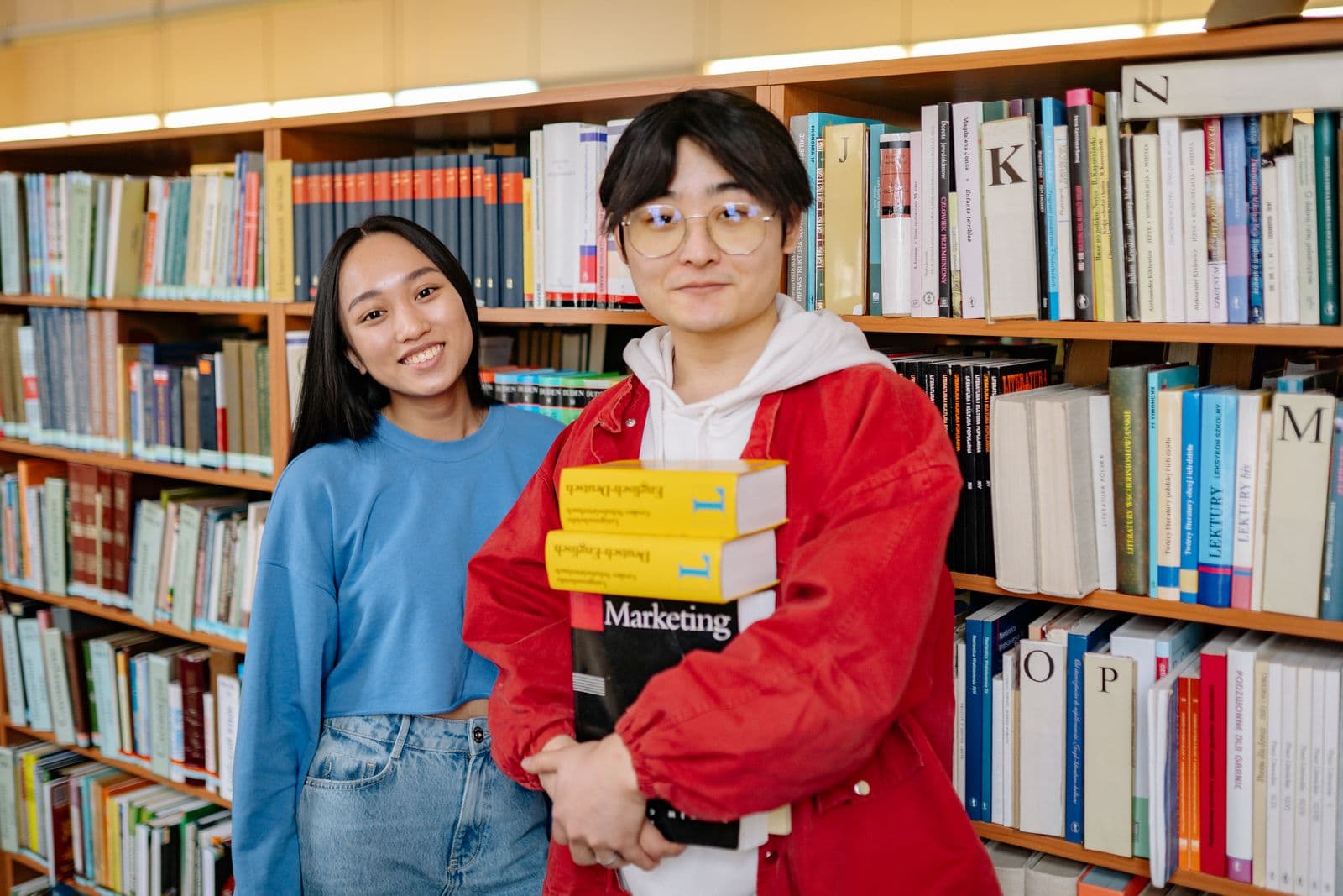 Deux étudiants souriants travaillant dans une bibliothèque