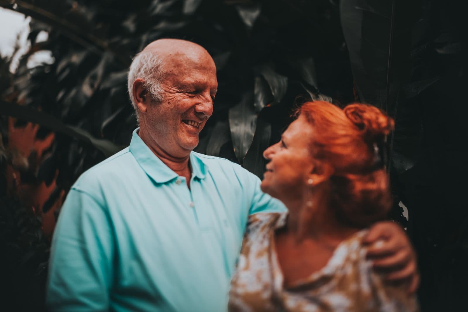 Couple âgé souriant, enlacé en extérieur